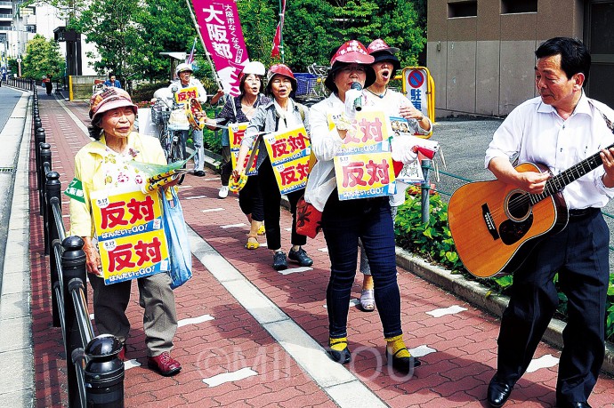 　下町の路地裏や大型商業施設でにぎわう上本町駅周辺などをギター伴奏に合わせて「守ろう大阪」を歌いながら路地裏を練り歩いて大阪市廃止・分割「反対」を訴える天王寺区の日本共産党員たち。道行く市民が「僕も反対。大阪市なくすなんて駄目」などと声援を送りました＝15日、天王寺区内