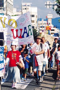 参加者が寄せ書きした横断幕を先頭にデモする市民＝23日、岸和田市内