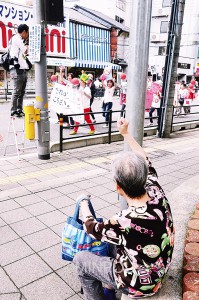 「ママの会＠池田」のパレードに、沿道からこぶしを上げて声援する人も＝18日、池田市内