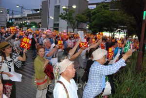 「戦争アカン」のステッカーを掲げながら「安倍と一緒の市政はいらない」とコールする市民＝６日、東大阪市内