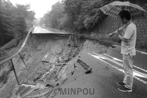 山から谷への土砂崩れが起き、約30メートルにわたって寸断された国道173号線。見ているのは中西能勢町議＝６日、能勢町内 