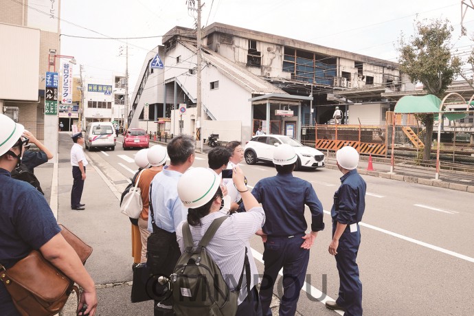 火災が起きた南海尾崎駅で焼失した駅舎や復旧状況を視察する一行ら＝７日、阪南市内