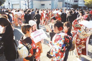 成人式の式典会場前で、シールアンケートで新成人と対話する民青同盟阪南地区委員会のメンバーら＝14日、岸和田市内