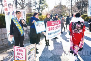 成人式の式典会場に向かう新成人に、「国民が主人公の政治をつくりましょう」と呼び掛ける、日本共産党のうち海公仁府議候補（東大阪市区）と東大阪市議ら＝14日、東大阪市内