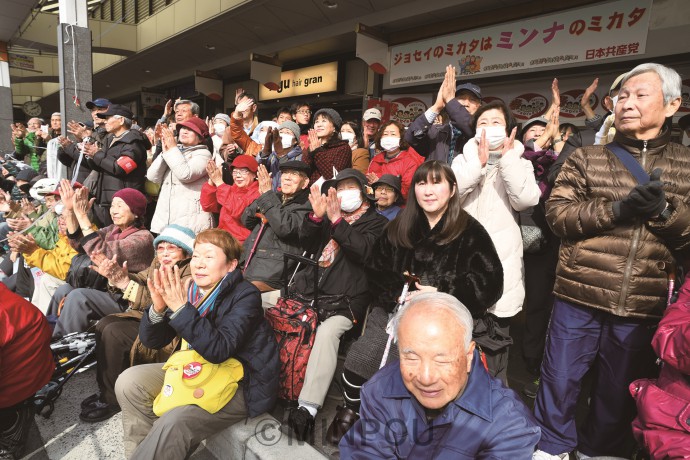 旭通商店街で志位委員長の訴えを聞く人たち＝２月24日、吹田市内 