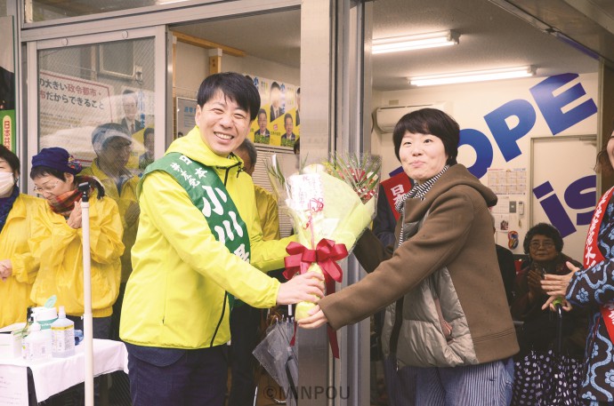 事務所開きで新婦人中央支部内後援会「アトム倶楽部」の花束を受ける小川氏（左）＝２月22日、大阪市中央区内 