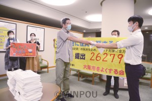 大阪市議会事務局に署名を提出する、よくする会の福井朗事務局長（中央）＝12日、大阪市役所内 