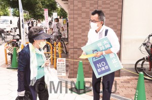 ビラを配りながら対話する市民＝20日、大阪市西区内