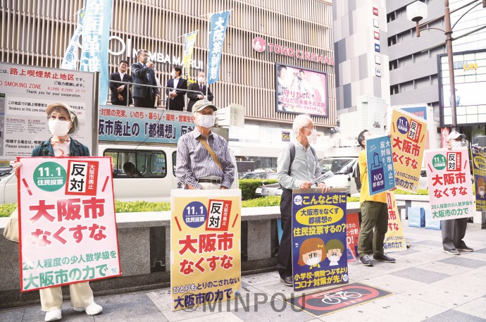 全国革新懇・大阪革新懇の街頭宣伝でプラスターを掲げながらビラを配る人たち＝９月26日、大阪市天王寺区内 